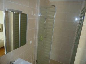W łazience znajduje się prysznic, umywalka i lustro. w obiekcie Apartment direkt am Strand w Okrugu Gornjim
