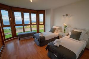 two beds in a room with a view of the ocean at Mirador del Mar in Oviñana