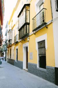 a yellow building with black balconies on a street at Mateo Alemán 22 in Seville