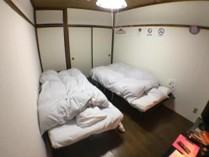 2 camas en una habitación pequeña con sábanas blancas en Kenroku Haitsu 302, en Kanazawa