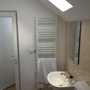 ein weißes Badezimmer mit einem Waschbecken und einem Spiegel in der Unterkunft Royal 60 in Oşorheiu