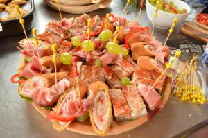 eine Platte mit Sandwiches mit Fleisch und Gemüse auf dem Tisch in der Unterkunft Pensiunea Popasul Iancului in Mărişel