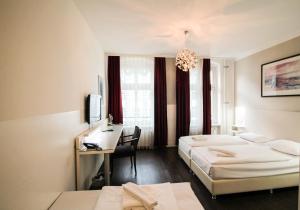 a hotel room with two beds and a desk at Hotel Prens Berlin in Berlin