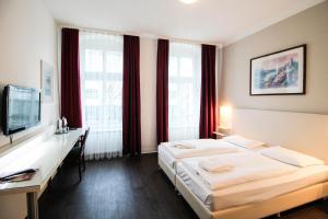 Dormitorio con cama, escritorio y TV en Hotel Prens Berlin, en Berlín