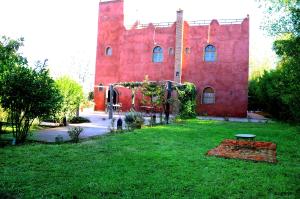 ein rotes Gebäude mit einem Rasenplatz davor in der Unterkunft Latifa House in Marrakesch