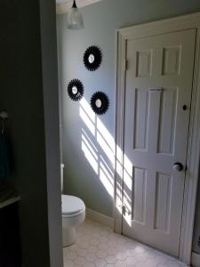 a bathroom with a toilet and a door with two sunburst mirrors at Woodland Retreat - Wanderlust in Woodland