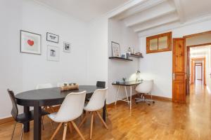 a dining room with a black table and white chairs at Flateli Aribau in Barcelona