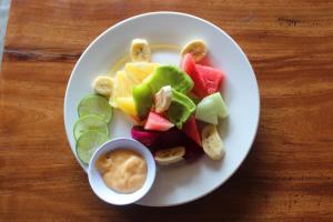 a plate of fruit and vegetables on a wooden table at The Mel Homestay in Nusa Penida