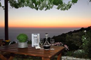 a wooden table with glasses of wine on it with the sunset at Panorama Villas in Drymon