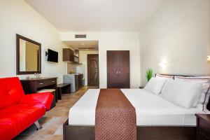 フォルカにあるBelohorizonte Fine Accommodationのベッドと赤いソファが備わるホテルルームです。