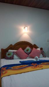 a bed with pillows and a light on the wall at Milan Home Stay in Ella
