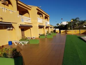 duży żółty budynek z dziedzińcem z zielonymi roślinami w obiekcie Apartamentos Olympia Garden w mieście La Manga del Mar Menor