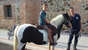 Młody chłopiec jeżdżący na koniu z mężczyzną w obiekcie El Rincón de Cabañeros w mieście Retuerta de Bullaque