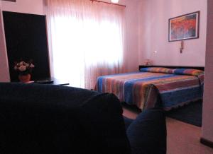 1 dormitorio con cama, ventana y sofá en Albergo Ristorante Cima I Pra', en Ponte nellʼAlpi