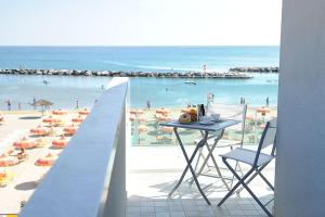 een tafel en stoelen op een balkon met uitzicht op het strand bij Hotel & Residence Cavalluccio Marino in Rimini