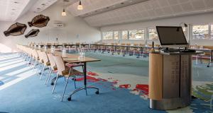 une salle de classe avec des tables et des chaises et un ordinateur sur un podium dans l'établissement Hotel Arctic, à Ilulissat