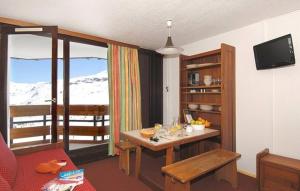 a living room with a table and a balcony with snow at Residence Tourotel in Val Thorens