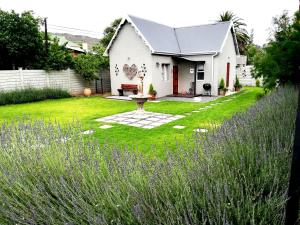 una casa bianca con un giardino con fiori viola di Tranquil House B&B @ 1 College Ave a Queenstown