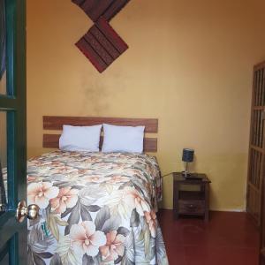 a bedroom with a bed with a floral bedspread and a table at Hospedaje Familiar Kitamayu Pisac in Pisac