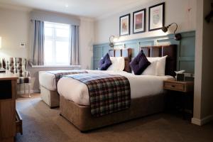 um quarto de hotel com uma cama grande e uma janela em The White Hart Hotel em Kingston upon Thames