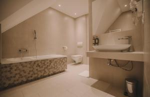 een badkamer met een wastafel, een bad en een toilet bij Hotel Restaurant Boss in Miłosław