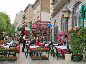 een straat met tafels en stoelen en mensen die rondlopen bij Margot Luxury Studio in Belgrado