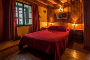 1 dormitorio con 1 cama con manta roja y ventana en Casa Elvira, en Tajace de Abajo