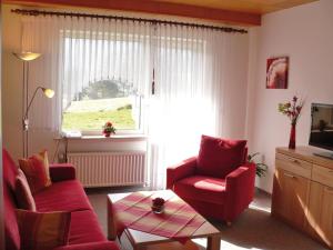 a living room with red furniture and a window at Haus am Stryckpark in Willingen