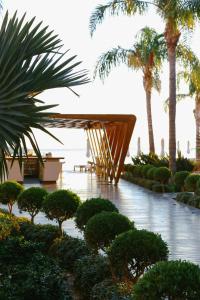 un jardín con una mesa de madera y palmeras en Alimounda Mare Hotel, en Karpathos