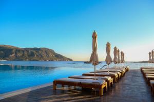 a row of wooden benches sitting on top of a beach at Alimounda Mare Hotel in Karpathos Town