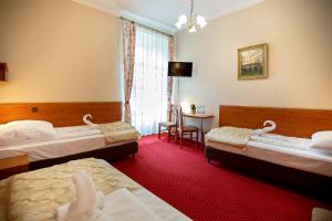 um quarto de hotel com três camas e uma mesa em Hotel Zamek Chałupki em Ruderswald