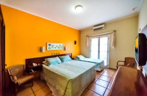 
a hotel room with a bed, chair, and nightstand at Pousada Villa Di Rimini in Ubatuba
