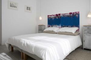 1 dormitorio con 1 cama blanca y una pintura azul en la pared en Tempo Lento, en Roma