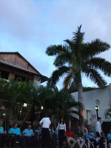 un groupe de personnes assises à des tables sous un palmier dans l'établissement Hotel Boutique Casa Berastegui, à Puerto Colombia