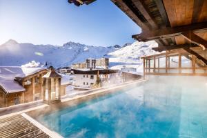 a swimming pool with snow covered mountains in the background at Hôtel les Campanules by Les Etincelles in Tignes