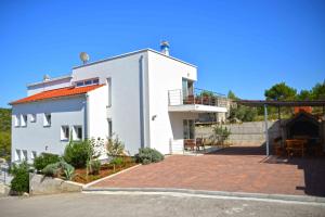 a white house with a patio in front of it at Apartments Bilanovic in Tisno