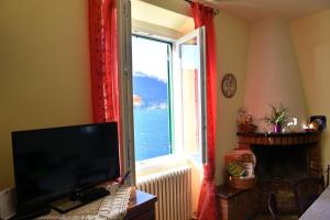 a living room with a television and a large window at La Cà del Menèc in Lierna