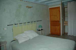 um quarto com uma cama com lençóis brancos e uma porta de madeira em Le Bellaton em Ambronay