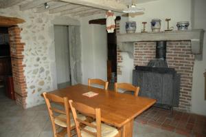 uma sala de jantar com uma mesa de madeira e um fogão a lenha em Le Bellaton em Ambronay