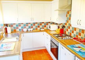 The Beach House! Just Steps from the Beach & Attractions - Perfect for Couples & Family Stays with Private Parking, Large Garden & Fast Free WiFi - The Perfect Seaside Getaway to Sutton on Sea في ساتون أون سي: مطبخ بخزائن بيضاء وفرن موقد