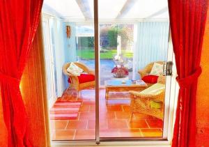 a screened in porch with red curtains and a living room at Coconut Cottage - A Romantic Cosy Cottage by the Sea! - You'll love this adorable Seaside Gem Just a few steps from the Beach! Perfect for Couples & Family's in Sutton on Sea