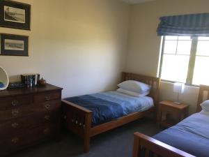 a bedroom with two beds and a dresser and a window at Pahau Downs in Culverden