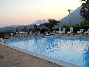 uma grande piscina com cadeiras e mesas brancas em Oasi Verde em Giffoni Sei Casali