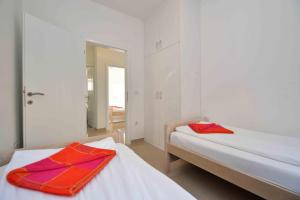 two beds in a white room with red towels on them at Apartments Bilanovic in Tisno