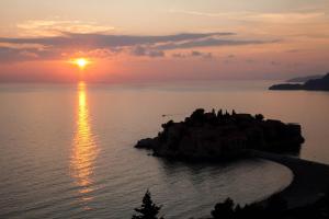 a sunset over a small island in the water at Villa Edelweiss in Sveti Stefan