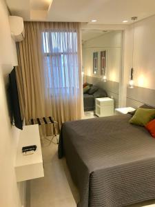 1 dormitorio con 1 cama, TV y sofá en Leblon Flat, en Río de Janeiro