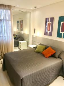 1 dormitorio con 1 cama grande con almohadas de color naranja y verde en Leblon Flat, en Río de Janeiro
