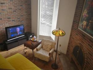 a living room with a couch and a tv and a lamp at Margie Townhome Suites in Toronto