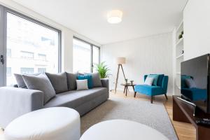 een woonkamer met een grijze bank en blauwe stoelen bij FLH Avenida da Liberdade Luxus in Lissabon