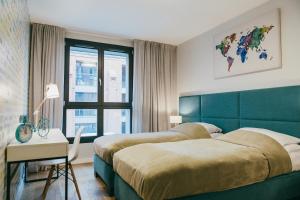 1 dormitorio con 2 camas, escritorio y ventana en Eight - Luxury Apartment with Beautiful View, en Cracovia